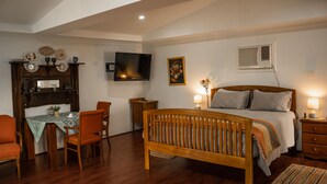 A bedroom with a wooden bed, a TV mounted on the wall, a desk with chairs, and a small table with a vase. - Charming Rural Escape in Mumballup - Views, Fire Pit, Walks & Pet-Friendly Stay (Mumballup)
