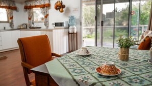 A dining area with a table set for two, featuring a floral tablecloth, a teapot, and a vase with flowers. - Charming Rural Escape in Mumballup - Views, Fire Pit, Walks & Pet-Friendly Stay (Mumballup)