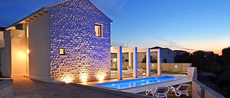Relax by the pool in a serene outdoor space with a bathtub and lounge chairs.