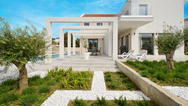 Une maison moderne dotée d’un espace extérieur couvert, d’une piscine et d’un jardin.