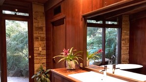 Une salle de bain dotée de meubles en bois, d’un double lavabo et d’une grande fenêtre donnant sur un paysage verdoyant.