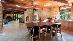 Une cuisine spacieuse avec une grande table et des chaises en bois, des murs en pierre et une cheminée en pierre.