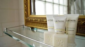 A bathroom with a glass shelf holding toiletries including body wash, hair wash, and moisturizer. - Friendly meeting chapel (North Adelaide)
