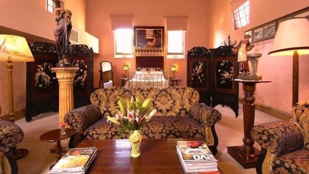 A room with a sofa set, a table with a vase of flowers, and a statue. - Friendly meeting chapel (North Adelaide)