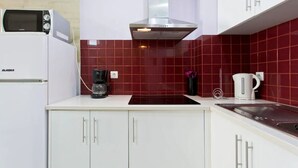 Een moderne keuken met witte kastjes, een backsplash van rode tegels, een ingebouwde magnetron, een koffiezetapparaat en een waterkoker.
