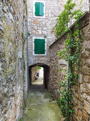 Un estrecho callejón de piedra con un edificio rústico de piedra a la izquierda y una construcción de madera a la derecha.