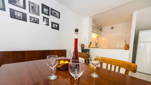 Comedor con una mesa de madera, tres copas de vino, un cuenco de limones y una botella roja.