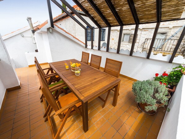 Une table en bois avec des chaises, un sol carrelé et des plantes en pot.