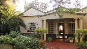 A building with a garden entrance, columns, and a red pathway leading to the door.