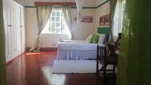 A bedroom with a bed, a desk, and a window with curtains.
