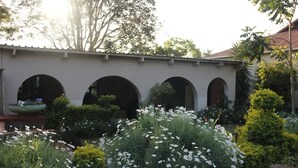 A courtyard with arches, lush greenery, and white flowers.