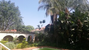 A courtyard with a pool, palm trees, and a building with arches.