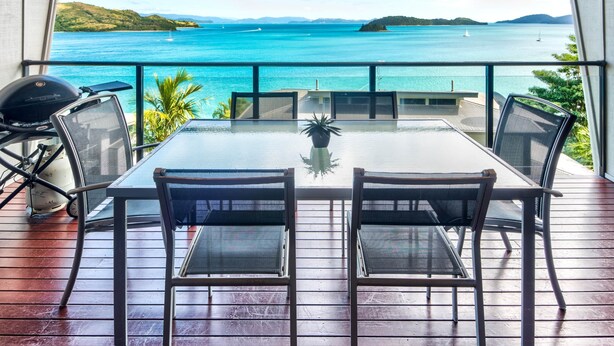 A dining area with a table and chairs, overlooking a scenic ocean view. - Shorelines 26, Seaview Apartment on Hamilton Island (Hamilton Island)