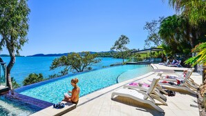 A poolside area with lounge chairs, a hot tub, and a view of the sea. - Shorelines 26, Seaview Apartment on Hamilton Island (Hamilton Island)