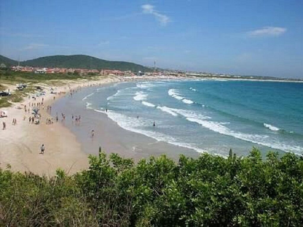 Une plage animée, un ciel dégagé et des collines à l’horizon.