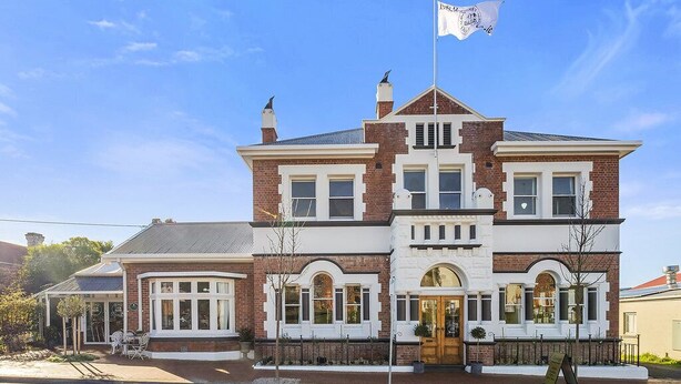 A Victorian-style building with a prominent central entrance, large windows, and a flag on top. - CygnetOldBank- Accommodation, Cafe Escape the everyday, style & bliss (Cygnet)
