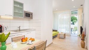 Een moderne keuken met een magnetron, spoelbak en een eethoek met een tafel en stoelen.