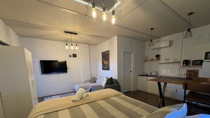 A modern room with a bed, a TV, a kitchen area, and a white brick wall. - Apartment 37 on Lemon (Mildura)
