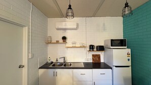 A compact kitchen with white cabinets, a black countertop, a microwave, a coffee maker, and hanging pendant lights. - Apartment 37 on Lemon (Mildura)