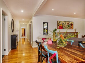A dining area with a wooden table, colorful chairs, and a painting on the wall.