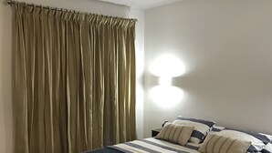 Ein Schlafzimmer mit Bett, Vorhängen, Deckenventilator und einer Wandleuchte.