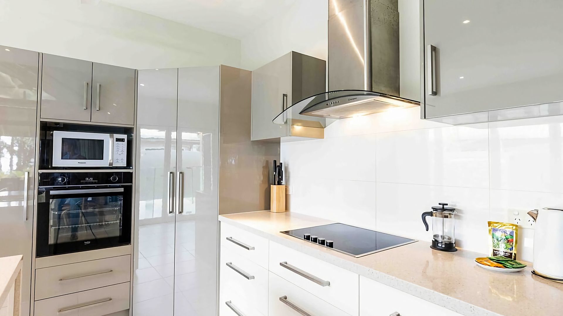 A modern kitchen with stainless steel appliances, a built-in oven, microwave, and a range hood.