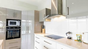 Une cuisine moderne équipée d’appareils électroménagers en acier inoxydable, d’un four encastré, d’un four à micro-ondes et d’une hotte aspirante.