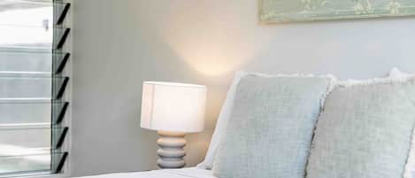 A bedroom with a bed, a nightstand with a lamp, and a painting on the wall.