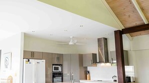 Una cocina moderna con una isla central, electrodomésticos de acero inoxidable y un ventilador de techo.