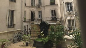 A courtyard with a central fountain, surrounded by potted plants and bicycles. - Brand new chic 30 m2 for 4, quite, in the best part of the hypest 9th district (Paris)