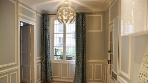 A room with a wooden floor, white walls, a large window with curtains, and a chandelier. - Brand new chic 30 m2 for 4, quite, in the best part of the hypest 9th district (Paris)