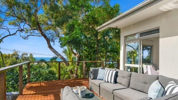 A balcony with a grey sofa, cushions, and a small table with two white bowls. - Tropical Family Oasis, Sunshine Beach (Sunshine Beach)