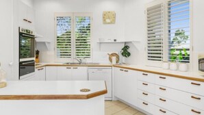 A modern kitchen with white cabinets, wooden countertops, and a central island. - Tropical Family Oasis, Sunshine Beach (Sunshine Beach)