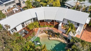 A modern house with a curved roof, a swimming pool, and a patio area. - Tropical Family Oasis, Sunshine Beach (Sunshine Beach)