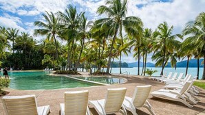 A poolside area with lounge chairs and palm trees. - Hibiscus 107 - Hamilton Island (Whitsundays)