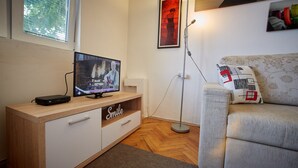 Een moderne woonkamer met een houten tv-meubel, een bank en een vloerlamp.