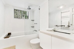 Enjoy a refreshing shower in the sleek bathroom with a large mirror, glass-enclosed shower, and separate toilet area.