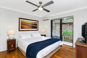 Relax in comfort with a large bed, ceiling fan, and framed artwork, plus a sliding door to an outdoor area with a view.