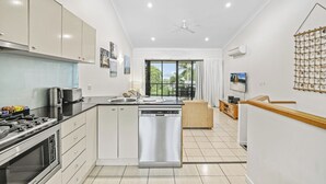 Una cocina moderna equipada con lavavajillas, estufa y microondas. Hay una zona de comedor con mesa y sillas.