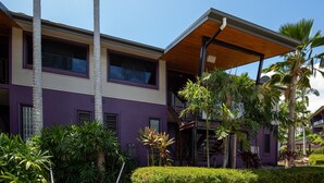 Un edificio moderno de dos pisos con fachada morada y un espacio exterior cubierto.