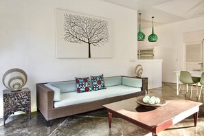 A living room with a sofa, a coffee table, a decorative bowl, a wall art piece, and a side table.