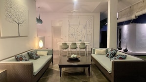 En moderne stue med to sofaer, et spisebord og et sofabord. Vægkunst af et træ og abstrakt kunst.