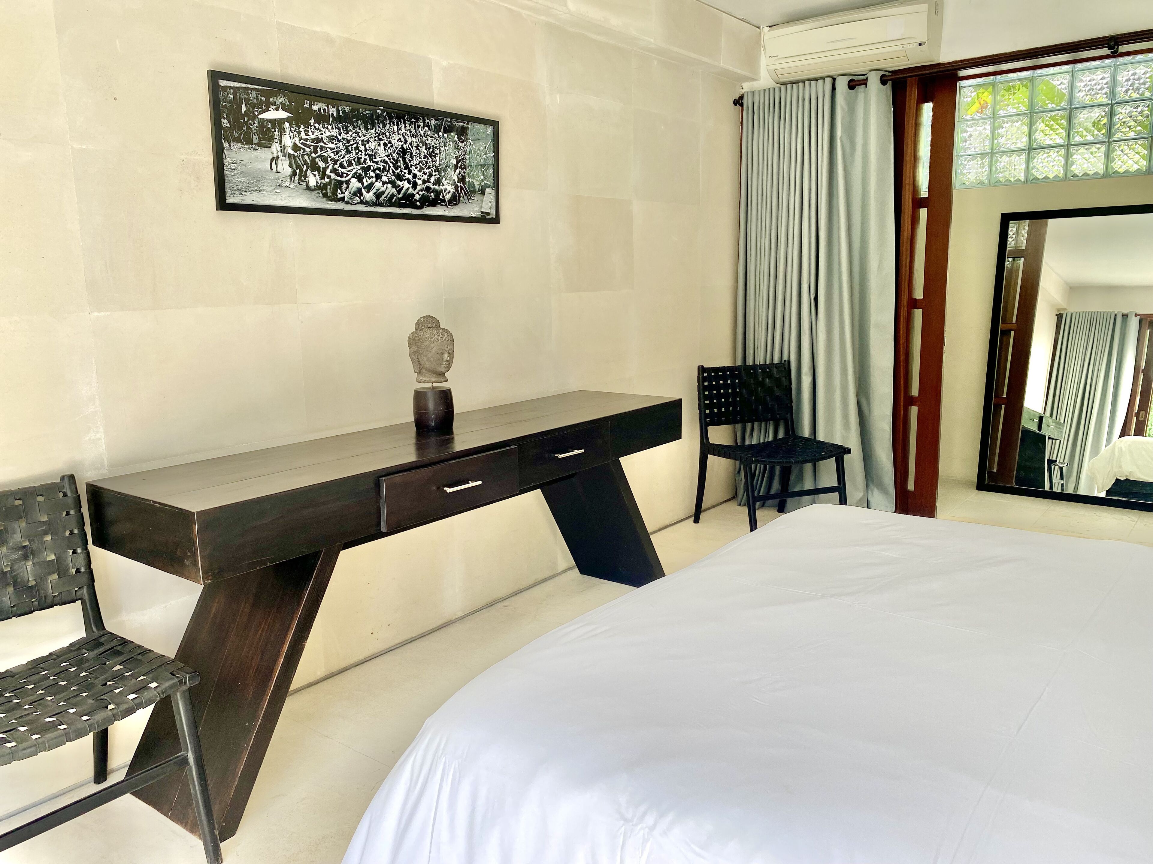 Ein Hotelzimmer mit Bett, Schreibtisch mit Stuhl, einem großen Spiegel und einem Bild an der Wand.