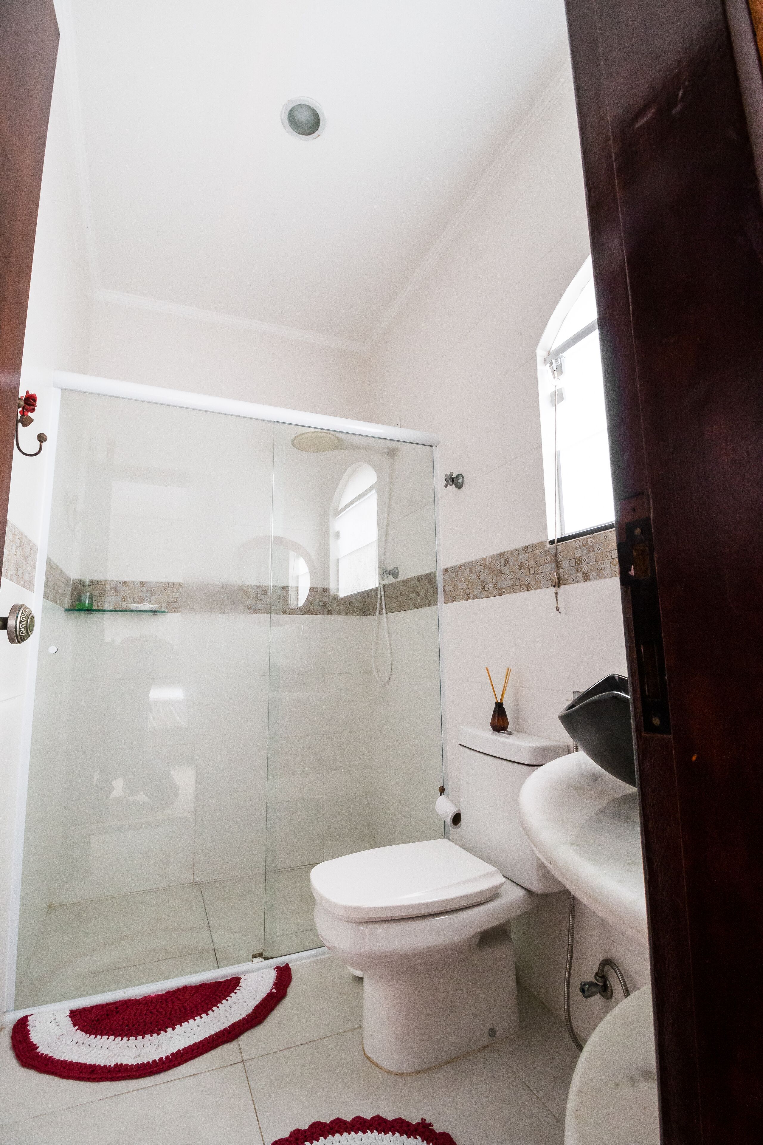 Un baño con ducha envuelta en vidrio, inodoro blanco y lavabo con espejo.