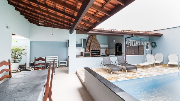 Un'area esterna coperta con piscina, sedie a sdraio e un angolo barbecue.