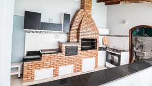 Una cucina con forno a mattoni, mobili bianchi e ventilatore a soffitto.