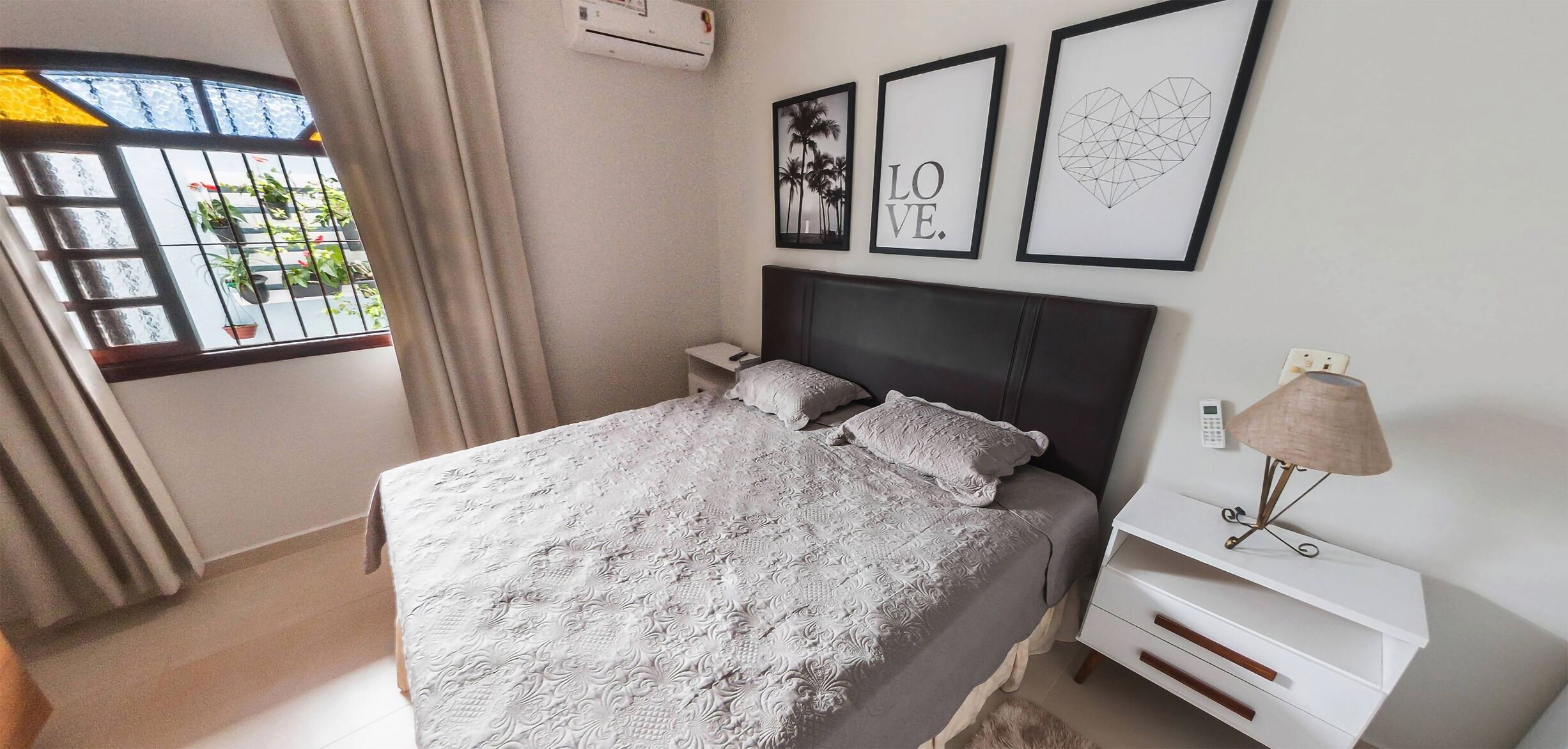 A neatly arranged bedroom with a bed, bedside tables, a lamp, and framed pictures on the wall.