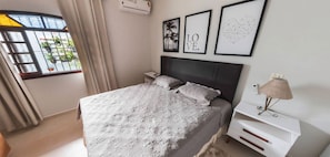 Une chambre à coucher bien rangée, avec un lit, des tables de chevet, une lampe et des tableaux encadrés accrochés au mur.
