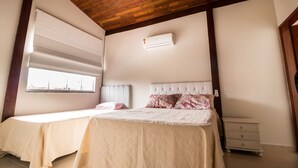 Una camera da letto con soffitto in legno, una finestra con persiane, un letto con copriletto trapuntato e un comodino.