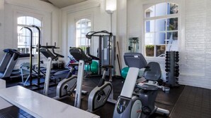 Un gimnasio con cintas de correr, máquinas de pesas y una pelota de ejercicio verde.